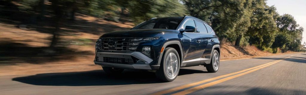 A 2026 Hyundai Tucson driving along a scenic road surrounded by greenery.