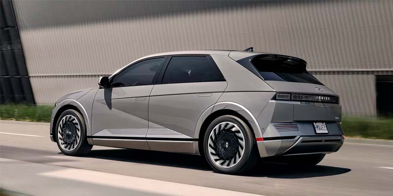 Hyundai IONIQ 5 driving on road near industrial building