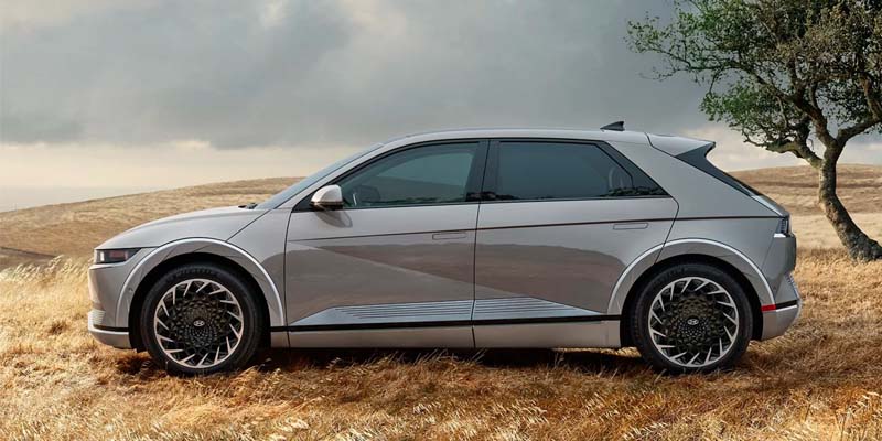 Rear view of Hyundai IONIQ 5 parked on dry grassy field