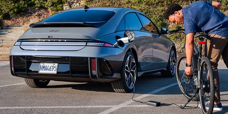 Man inflating bike tire using electric car power outlet