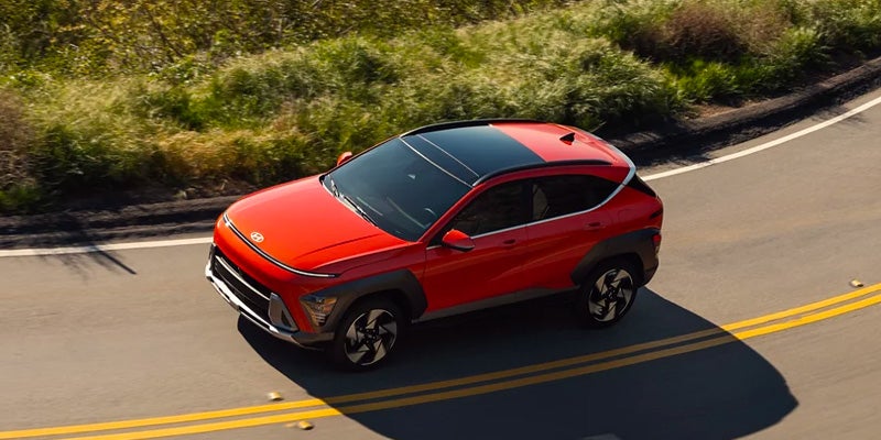Red Hyundai Kona in motion on the road