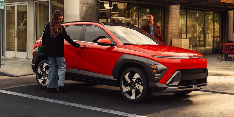 Couple opening car door of Hyundai Kona parked near a roadside shop
