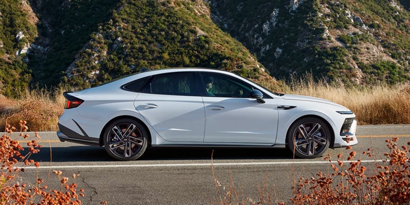 Hyundai Sonata parked on road with mountains in the background